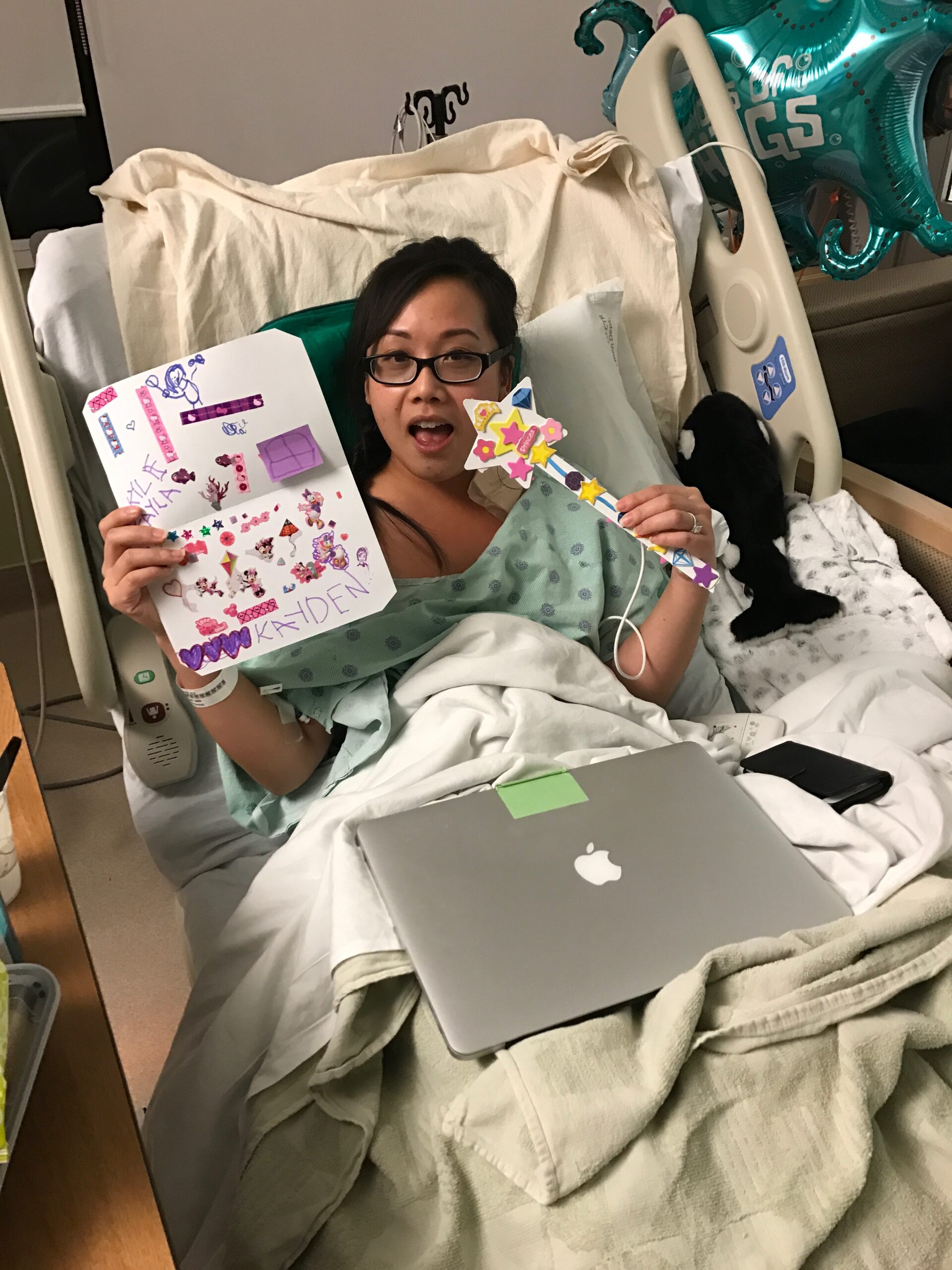 Stephanie in a hospital bed posing with cards during treatment