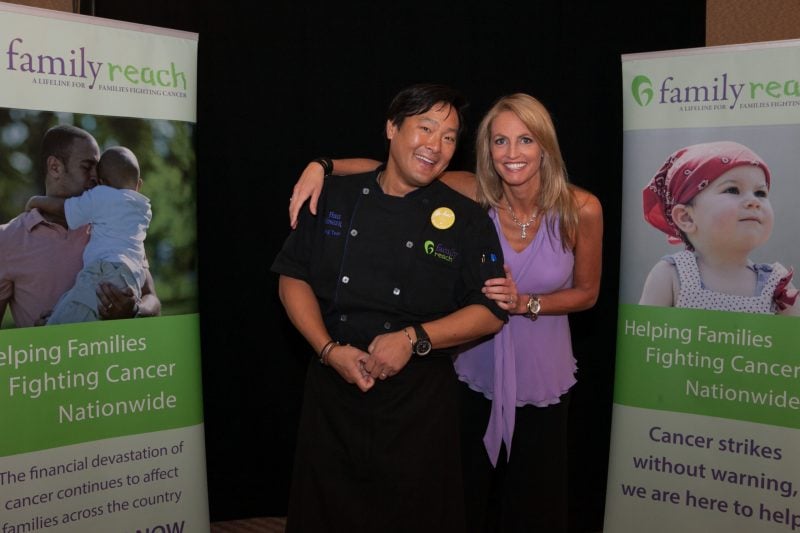 Chef Ming Tsai and Carla Tardif posing in front of Family Reach signs